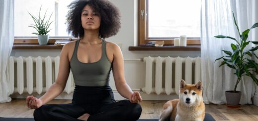 A woman and a dog sitting on a yoga mat