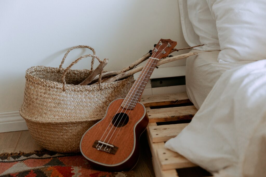 A bed with wooden boards, a woven basket, and a guitar next to it.