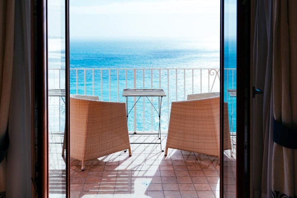 Two wicker chairs on a balcony overlooking the ocean