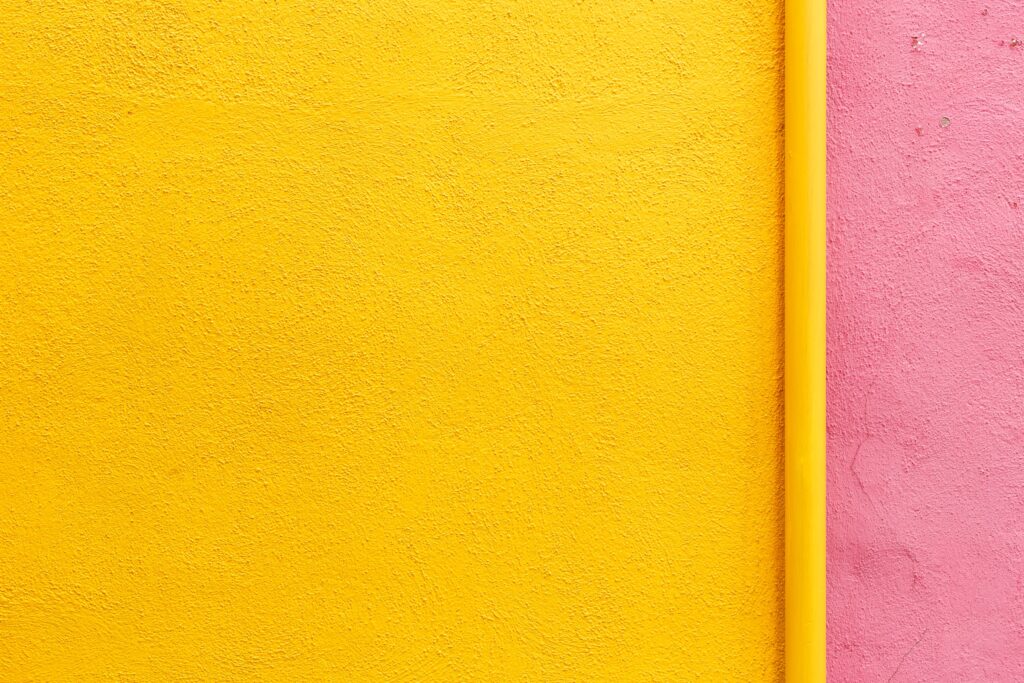 A wall painted yellow and pink because freshly painted walls are one of the best tips for decorating your home office.