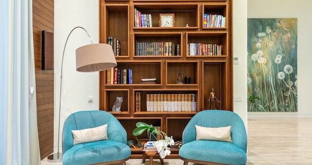 Blue padded chairs near the lamp and wooden bookshelves