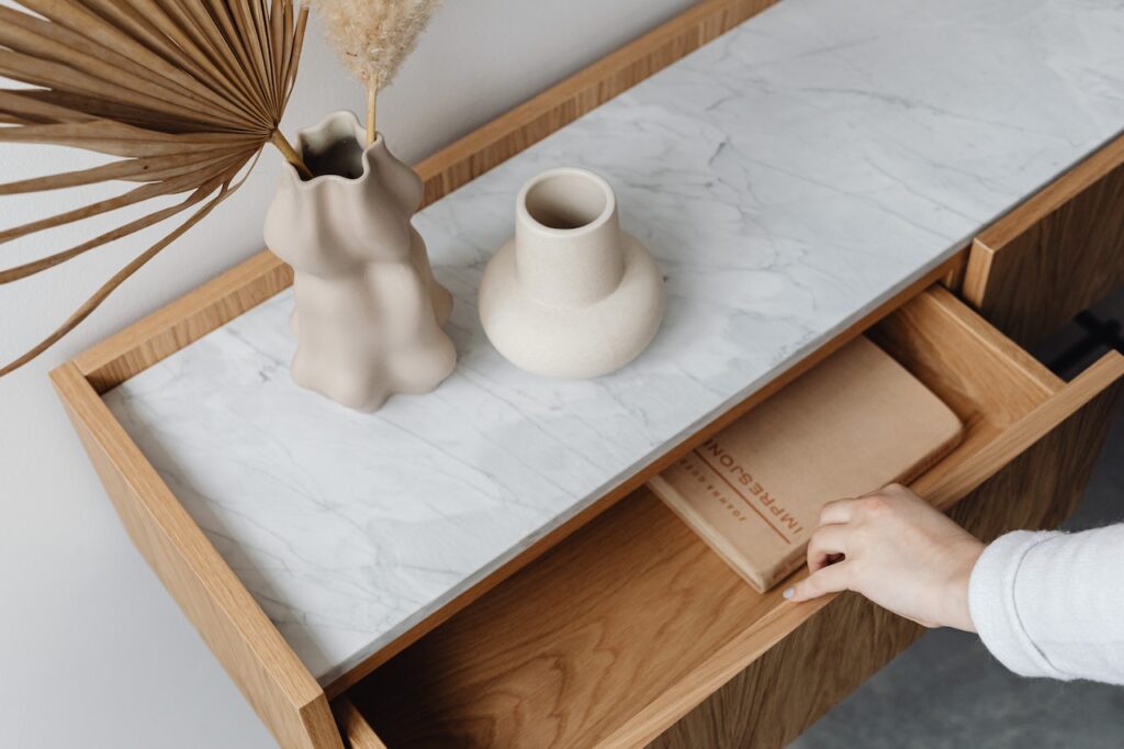 A person opening a drawer of a desk with minimalistic decor.