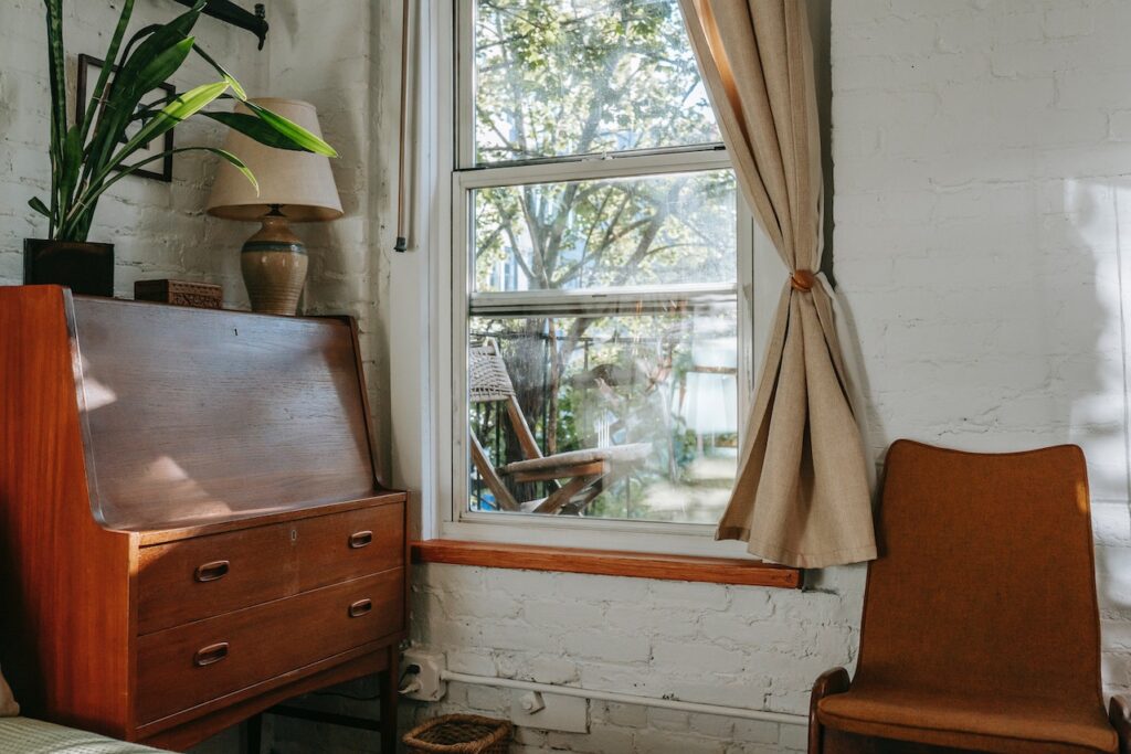 A mid-century modern desk next to a window.