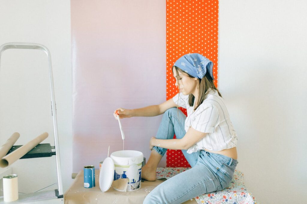 A woman with a bandana installing orange wallpaper.